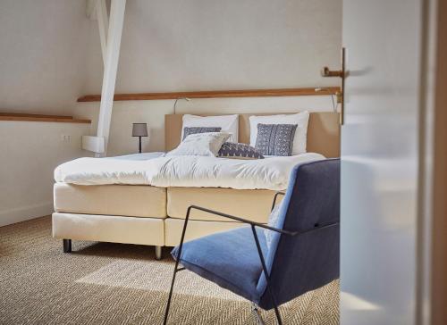a bedroom with a large bed and a blue chair at Herberg de Zwarte Ruiter in Gulpen