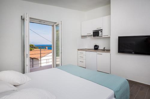 a room with two beds and a kitchen with a balcony at Apartments Panorama in Lokva Rogoznica
