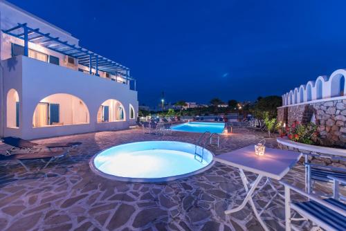 a swimming pool in a resort at night at Hotel Olympia in Karterados