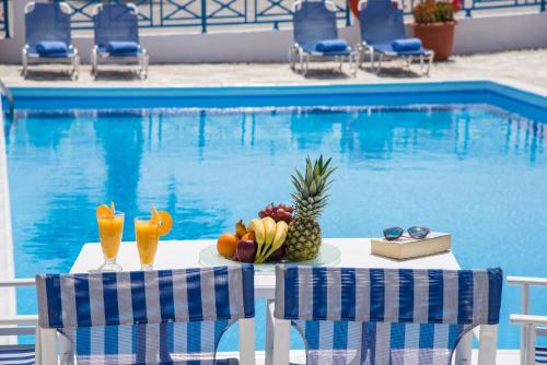 a table with fruit and drinks next to a swimming pool at Hotel Olympia in Karterados