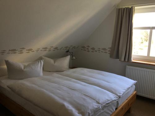 a bedroom with a bed with white sheets and a window at Ferienwohnung Gänseweg in Graal-Müritz
