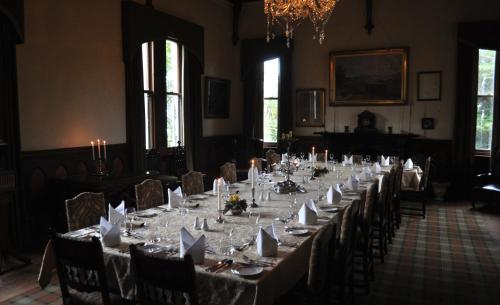 a long table in a room with tables and chairs at Larnach Lodge & Stable Stay in Dunedin