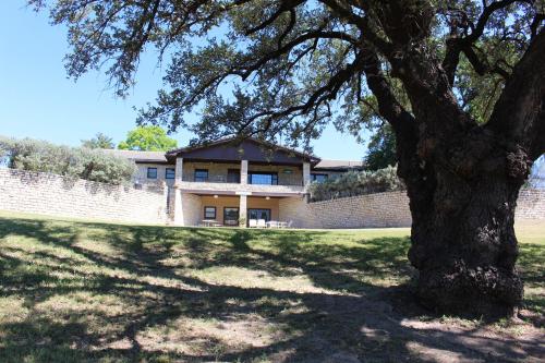 a house behind a brick wall with a tree at Live Oak B&B in Glen Rose
