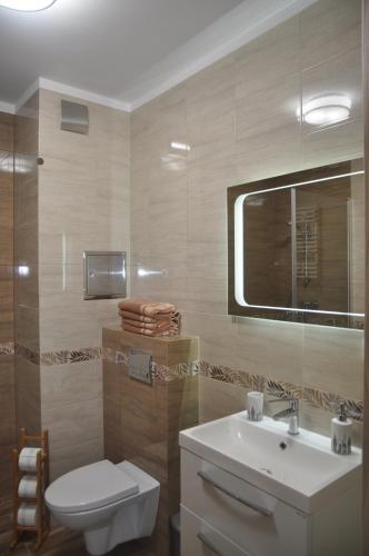 ein Badezimmer mit Waschbecken, Toilette und Spiegel in der Unterkunft Apartament Berlin in Świnoujście