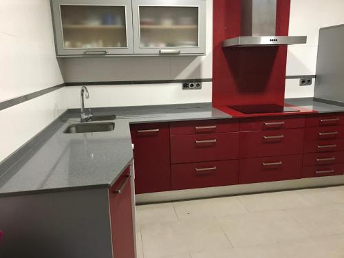- une cuisine avec des placards rouges et un évier dans l'établissement Casa Pareada en Peñiscola, à Peñíscola
