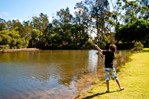 a young boy standing by a lake with his arm in the air at Lani's Holiday Island in Forster