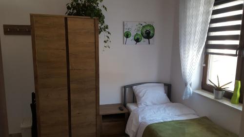sypialnia z łóżkiem, szafką i oknem w obiekcie DobraNocka w mieście Kaleń