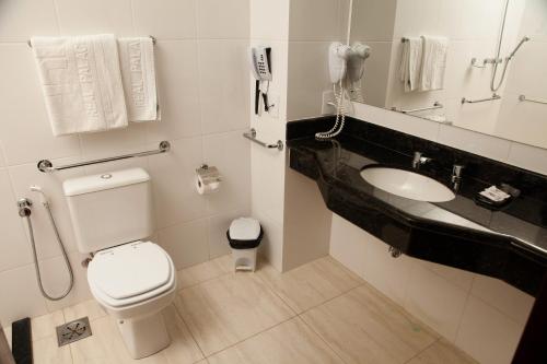 a bathroom with a toilet and a sink and a phone at Real Palace Hotel in Santa Rita do Sapucaí