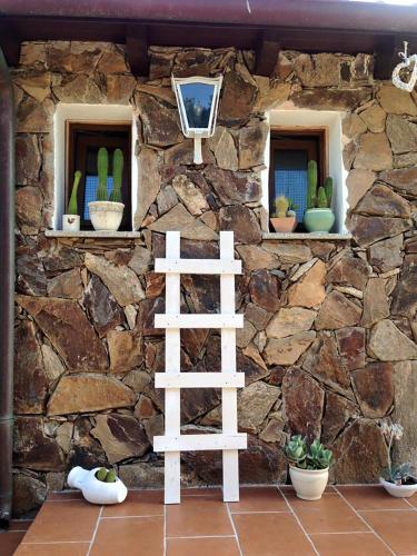 a stone wall with two windows and a white ladder at B&B La Tasgia in Aggius