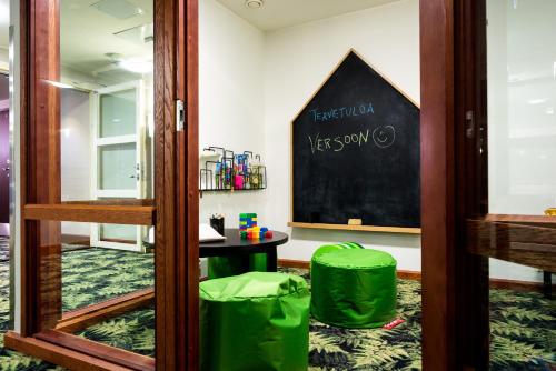 a classroom with a blackboard and green stools at Hotel Verso in Jyväskylä