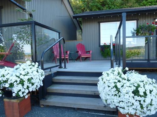 a porch with two pink chairs and some flowers at Driftwood by the Sea Inn in Campbell River