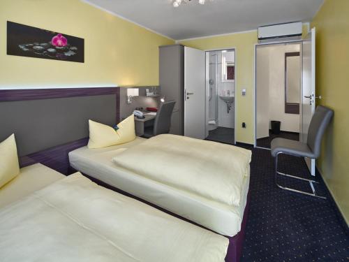 a hotel room with two beds and a desk at Hotel Alfa Zentrum in Munich
