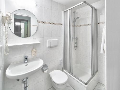 a bathroom with a shower and a toilet and a sink at Hotel Alfa Zentrum in Munich