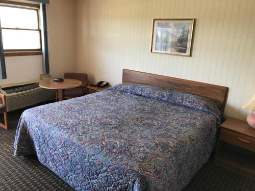 a bedroom with a bed and a table and a window at Exxon Quik Stop & Motel in Wausaukee