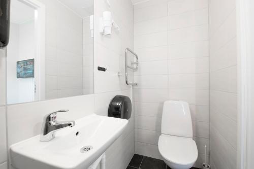 La salle de bains blanche est pourvue d'un lavabo et de toilettes. dans l'établissement Hotell Eken Mölndal, à Mölndal
