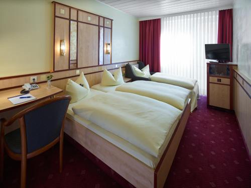 a hotel room with two beds and a desk at Hotel Alfa Zentrum in Munich