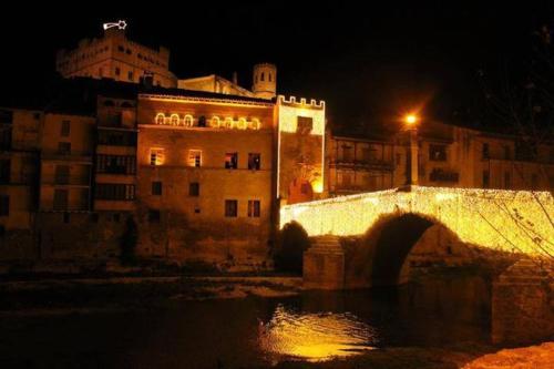 a bridge over a river with a building at night at Apartamentos Casa Ferrás in Valderrobres