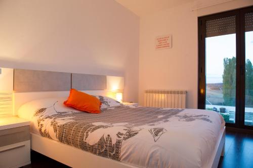 Schlafzimmer mit einem Bett mit orangefarbenem Kissen in der Unterkunft La Espiga in Cortos