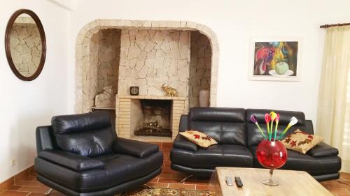 a living room with black leather furniture and a fireplace at Villa Quinta da Violeta in Loulé