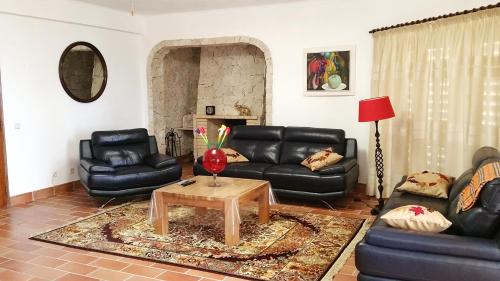 a living room with black leather furniture and a table at Villa Quinta da Violeta in Loulé