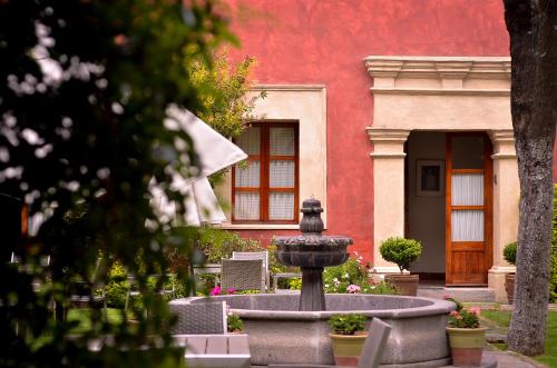 a fountain in front of a building with a red wall at Quinta Luna in Cholula