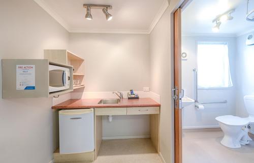 a small bathroom with a sink and a microwave at Bella Vista Motel Hamilton in Hamilton