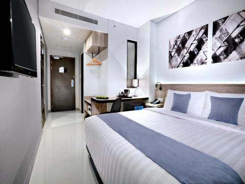 een hotelkamer met een groot bed en een televisie bij Hotel Neo Gajah Mada Pontianak by ASTON in Pontianak