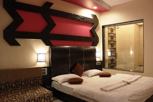 a bedroom with a bed with a black and red headboard at JS Excellency in Mahabaleshwar
