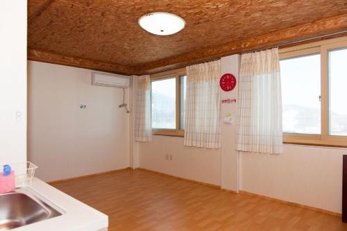 an empty kitchen with a sink and windows at Sunrise Pension in Hwaseong