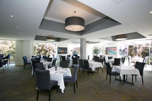 une salle à manger avec des tables blanches, des chaises et des fenêtres dans l'établissement Best Western Plus Apollo International, à Newcastle