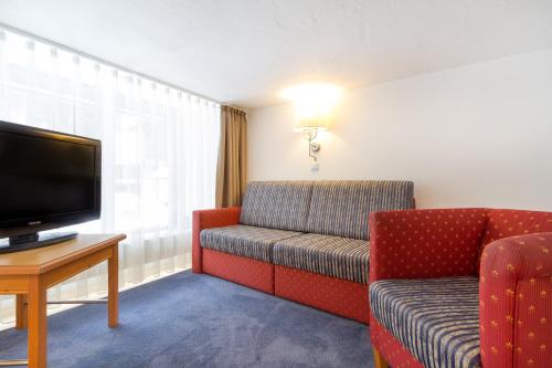 a hotel room with a couch and a television at Kienle - das Kräuterhotel in Balderschwang