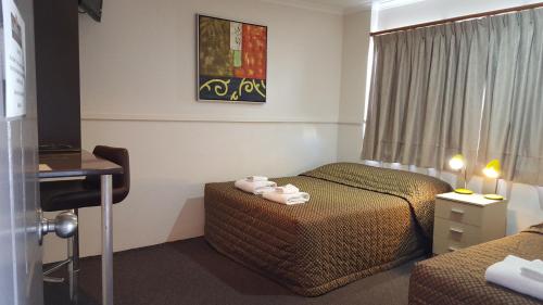 a hotel room with two beds and a desk at The Commercial Hotel Motel in Chinchilla