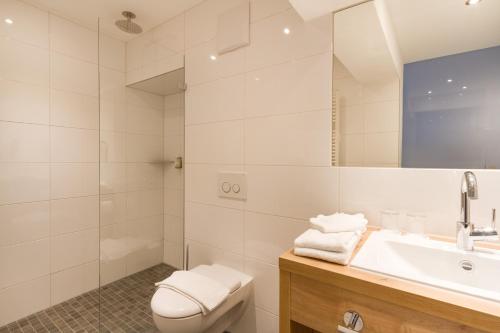 a white bathroom with a toilet and a sink at Kienle - das Kräuterhotel in Balderschwang