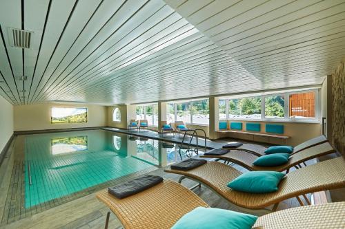 a pool with chairs and a swimming pool at Hotel Bad Rain in Oberstaufen
