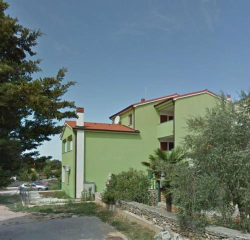zielony budynek z drzewami przed nim w obiekcie Apartment Beni w Medulinie