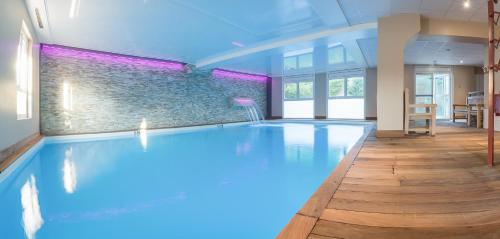 a large swimming pool with blue lighting in a room at Villa Odette in Deauville