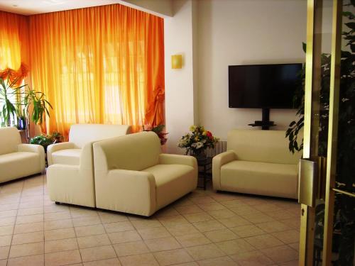 a living room with two white chairs and a flat screen tv at Hotel Geppi in Pietra Ligure