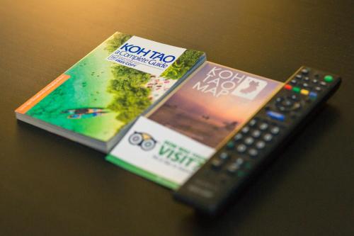 a remote control sitting next to a dvd and a book at Infinity Guesthouse in Ko Tao