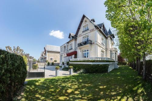 ein großes weißes Haus mit einem Hof in der Unterkunft Villa 81 in Deauville