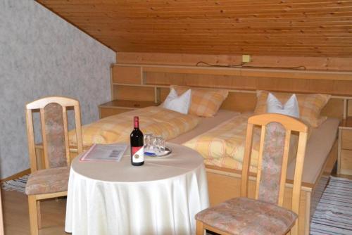 a table with a bottle of wine and two beds at Erlebnispension Zum Wanderer Sepp in Arnbruck