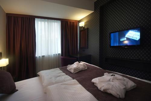 a hotel room with a bed and a flat screen tv at Hotel Park Doboj in Doboj