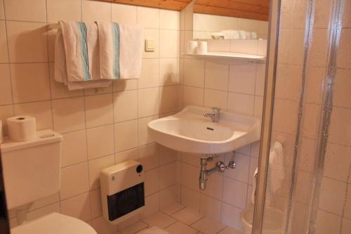 a white bathroom with a sink and a toilet at Pension Duregger in Faak am See