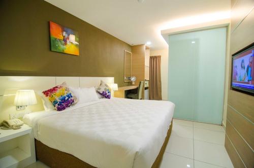 a hotel room with a large bed and a phone at Hotel Mornington Bukit Permata Lumut in Lumut