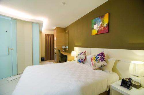 a bedroom with a large white bed and a desk at Hotel Mornington Bukit Permata Lumut in Lumut