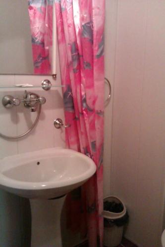 a bathroom with a sink and a pink shower curtain at Семеен хотел Калина Family hotel Kalina Говедарци in Govedartsi