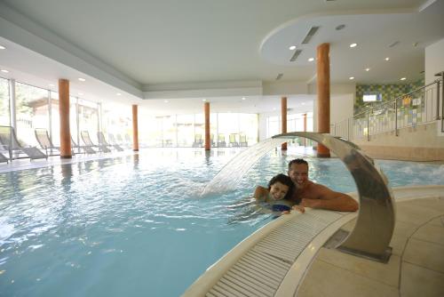 a man and a child in a swimming pool at Hotel & Alpin Lodge Der Wastlhof in Niederau