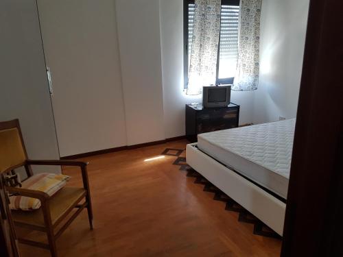 ein Schlafzimmer mit einem Bett, einem Stuhl und einem TV in der Unterkunft Appartamento di pregio In Piazza Durante Letojanni Taormina in Letojanni