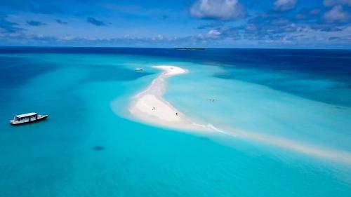 an island in the ocean with a boat in the water at Aveyla Manta Village in Dharavandhoo