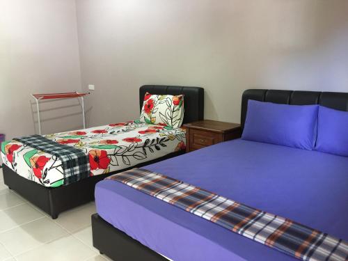 een slaapkamer met 2 bedden en een tafel met een stoel bij Harmony Guesthouse Sdn Bhd in Kampung Padang Masirat