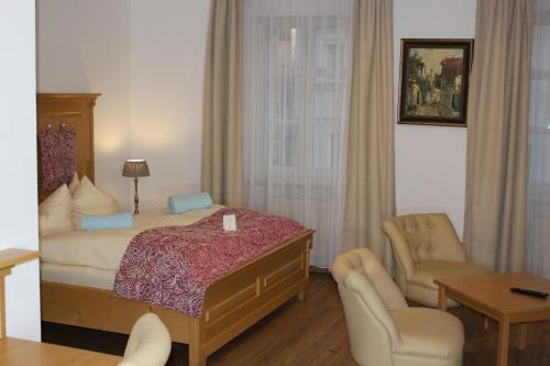 a bedroom with a bed and a chair and a table at Posthotel Arnold in Gunzenhausen